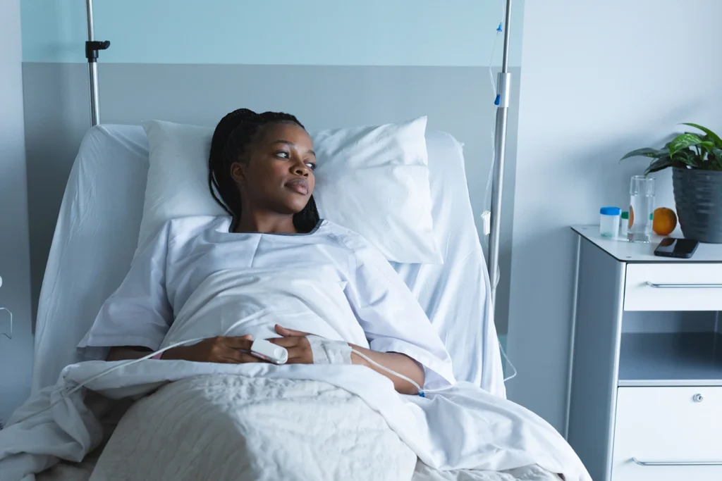 Uma mulher negra em uma cama de hospital. Ela está em busca de um advogado previdenciário especialista em Auxílio-Doença ou Auxílio por Incapacidade Temporária em Franca-SP